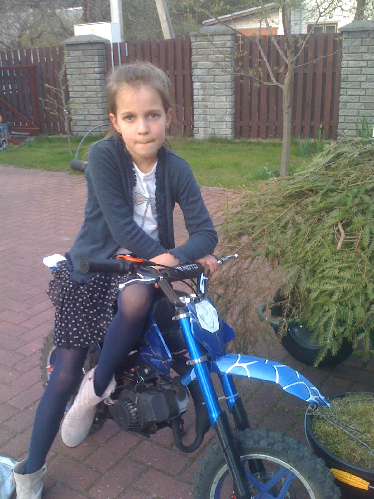 Mergaitė ant mėlyno vaikiško motociklo